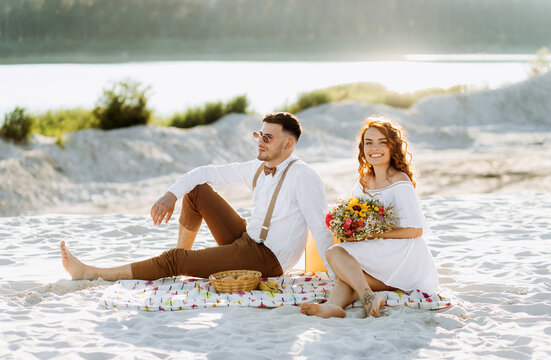 Sweet picnic on the sand near the lake in summer. Beautiful young couple