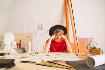 Sad girl Illustrator artist clutched head sitting at table in studio. State of apathy, frustration...