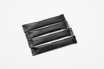 Sugar sticks on a white background. Sugar sticks without logo. Craft paper sugar bags. Sugar bags made of black paper. Mockup for applying a logo.