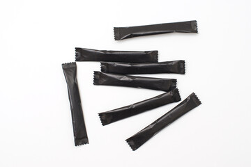Sugar sticks on a white background. Sugar sticks without logo. Craft paper sugar bags. Sugar bags made of black paper. Mockup for applying a logo.