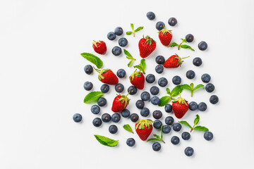 Strawberries and blueberries scattered on white background