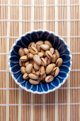 salted pistachio nuts in a blue round bowl top view. Pistachio is a healthy vegetarian protein nutritious food. Natural nuts snacks.
