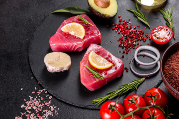Fresh tuna fillet steaks with spices and herbs on a black background