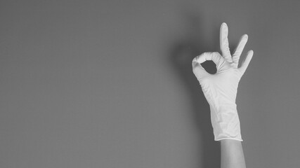 hand doing a ok hand sign and wearing blue medical gloves on white background.