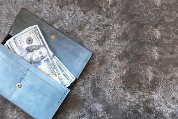 100 dollar bills in a blue wallet on a brown background. Cash. Place for your text.