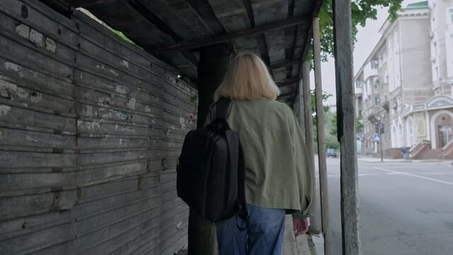 A woman with a backpack in walking along a pedestrian tunnel next to the roadway
