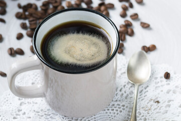 Coffee in a mug and some coffee beans in the background.