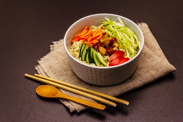 Traditional Korean noodle bowl with smoked chicken, fresh sliced vegetables and sesame seeds