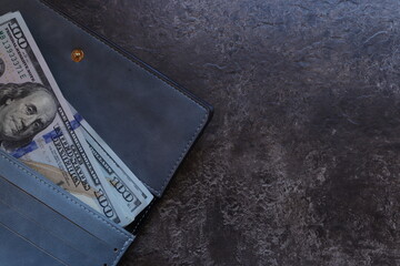 100 dollar bills in a blue wallet on a brown background. Cash. Business concept. Place for text