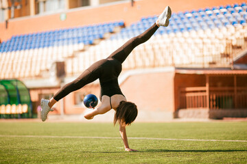 girl in black sport outfit doing doing gymnastics handstand in the splits © Bogdan