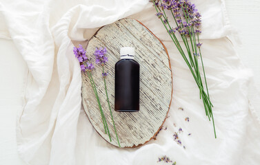 Lavender flowers with lavender essential oil bottle on white wooden rustic board and fabric....