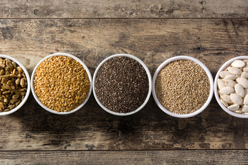 Assortment of different seeds in bowls on wooden table. Top view