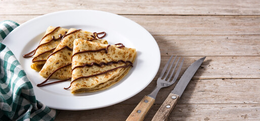 Sweet crepes with chocolate syrup on wooden table. Panorama view with copy space