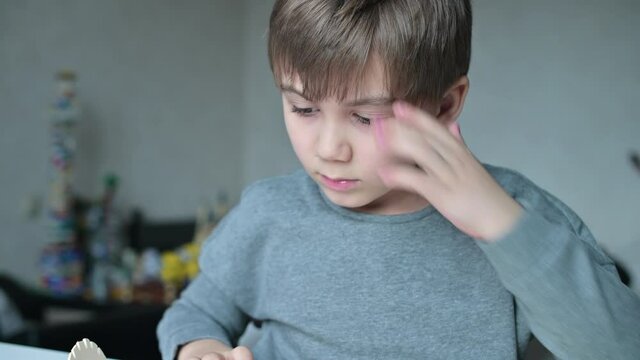 The child enthusiastically plays with the designer in his room at the table, close-up of the face