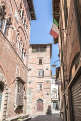 Fototapeta premium Street of Lucca in Italay, Tuscany. Hot summer day in an italian city with architecture and italian flag.