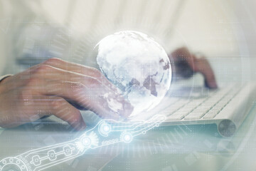 Double exposure of world map hologram with man working on computer on background. Concept of worldwideweb.