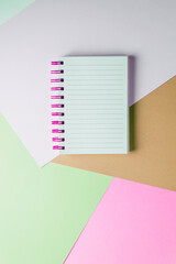 notebook with blank sheet and pink spiral on a colorful pastel background.