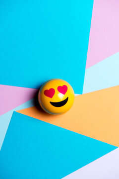 smiling yellow emoticon with heart eyes, on multicolored geometric texture