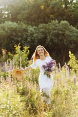 Drive girl in a white dress walks in a lupine field.