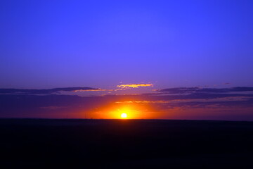 Fototapeta na wymiar Bright orange sun at sunset blue sky on the horizon