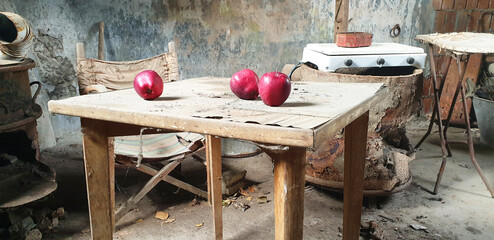 Red apples lie on an old table in an abandoned room.