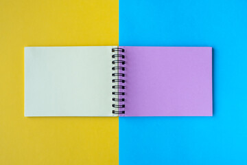 A notebook with multi-colored pages lies on a yellow and blue background. Top view, flat lay, copy space.