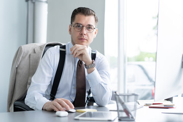 Male casual office worker smiling in office, sitting at workplace