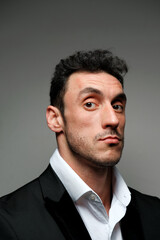 Close up portrait of a man 30-34 years old in a white shirt and a black jacket on a gray background. 