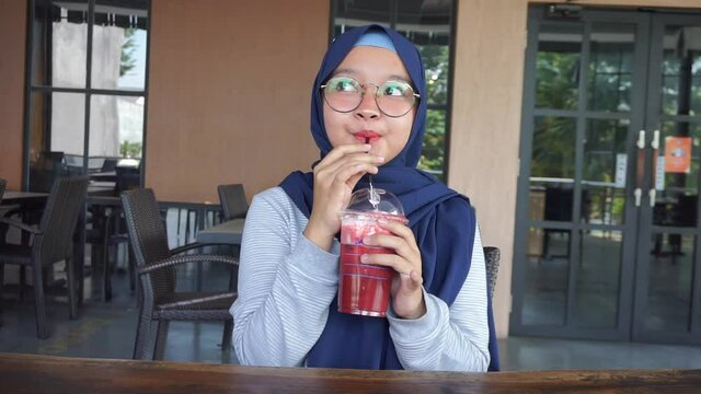 asian hiujab woman drinking red velvet on cafe