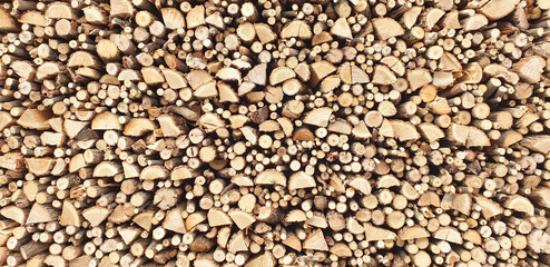 Background of stacked chopped firewood on a sunny day.