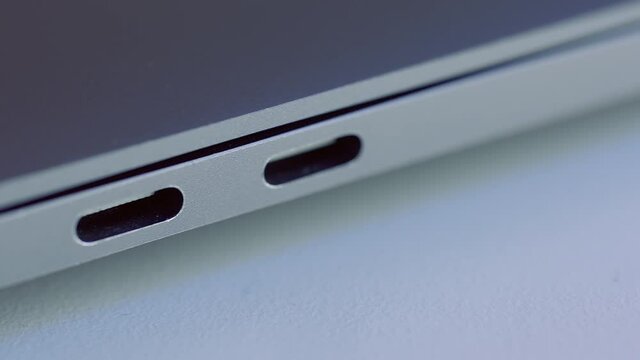 Close up of elegant modern laptop details. Action. Concept of modern technologies, USB port of a computer lying on white flat surface.