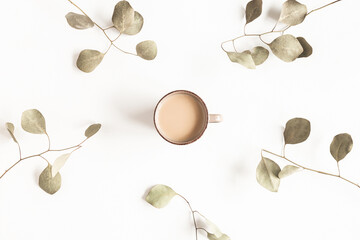 Autumn composition. Cup of coffee, eucalyptus leaves on white background. Autumn, fall, winter concept. Flat lay, top view