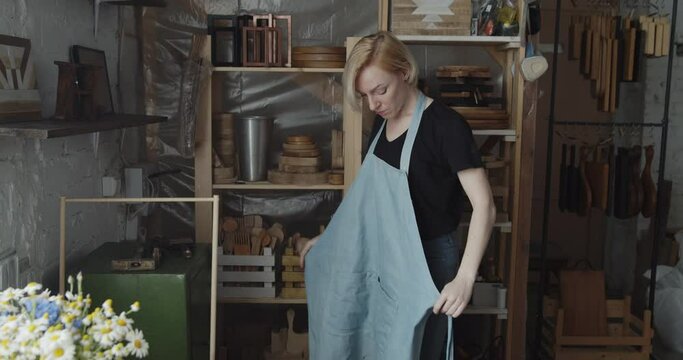 Woman carpenter puts on apron preparing for work