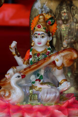 Fototapeta premium Antique Beautiful Colorful Artistic Handmade Handcrafted Religious Statue Of Indian Hindu Goddess Devi Saraswati Playing Classical Musical Instrument Veena Sitar For Worship Pooja Puja