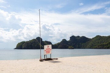A warning sign for the strong current at the sandy beach of Tanjung Rhu Beach in Langkawi,...