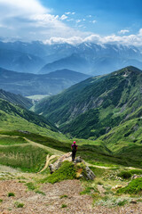 Fototapeta na wymiar A girl in a hat stands on a stone on the background of the Svaneti. Caucasus mountains in summer