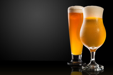 Different glasses and cups with beer, on a dark table, dark background and copy space