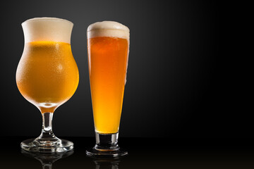 Different glasses and cups with beer, on a dark table, dark background and copy space