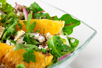 Salad with oranges, feta and arugula on white background