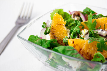 Salad with oranges, feta and arugula on white background