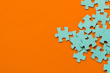 Puzzle. Many puzzle pieces on an orange background. The concept of collective thinking.