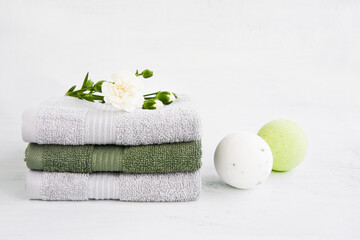 SPA concept. Two bath bombs and bath towels decorated with carnation flower on light background....