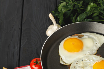 Fried egg in frying pan with sliced bread on wooden table