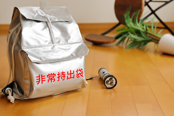 地震が災害による転倒物のある部屋と避難グッズと備蓄イメージ。