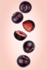 Falling plums isolated on a color background with clipping path. Flying food, fruit. Front view