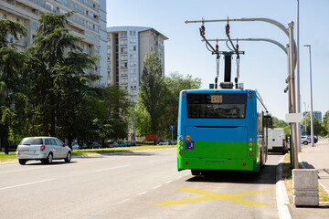 Electric bus at a stop is charged by pantograph	