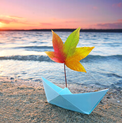 Segelboot aus Papier am Strand im Herbst