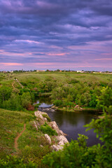 Fototapeta na wymiar View of the river, rocks and hills. Rushing water and suspension bridge. .Purple sunset sky