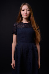 Young beautiful woman with long brown hair against black background