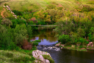 View of the river, rocks and hills. Rushing water and suspension bridge